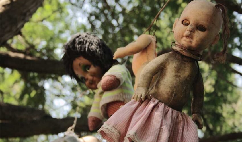 The island is full of dolls hanging from the trees, and the buildings are covered in cobwebs and insects, making it a haunting sight.